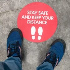 A sign on the floor of a shop, advising customers regarding sociala distancing guidelines.